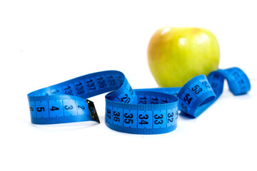green Apple and measuring tape on a white background, weight loss and healthy lifestyle
