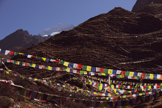 View of mountains near muktinath temple at mustang, Nepal with snow on summit. Blue sky sunny day and sun glare. Colorful prayer flags at the bottom