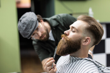 Beard styling and cut. Bearded man in barbershop corect his beard. So trendy and stylish....