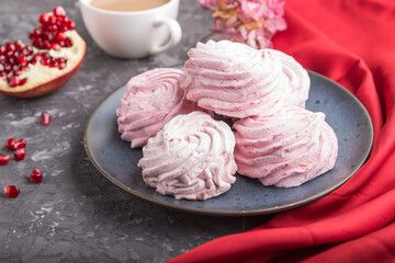 Pink pomegranate homemade zephyr or marshmallow with cup of coffee on a black concrete background. side view, selective focus.