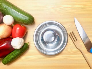 Receta verduras frescas con bol, tenedor de madera y cuchillo, utensilios de cocina en fondo de madera clara. Vegetariano. Pimiento, pepino, berenjena, zanahorias, ajo, judias verdes, tomate