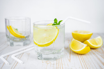 glass of soda water with ice, mint and lemon. refreshing summer cocktail concept with tonic or transparent alcohol