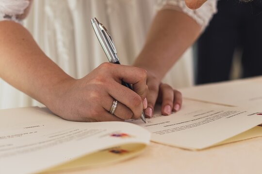 Close up shot of a bride and groom signing their marriage document