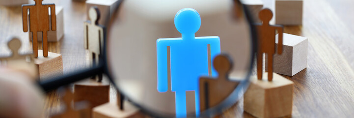 Searching for missing person in crowd of toy human figures with magnifying glass