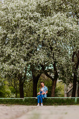 Obraz premium A little girl sits on her mother's lap in the flower garden in the summer.
