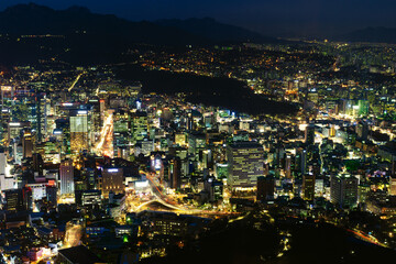 Fototapeta na wymiar Aerial view of downtown Seoul in the early evening hours, portraying a busy city life with mountains in the background, viewed from the top of Seoul Tower