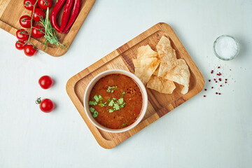 Top view on tasty, traditional soup Kharcho with beef, rice, cherry plum puree and chopped walnuts in ceramic bowl on wooden background. Tasty Georgian cuisine