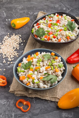 Pearl barley porridge with vegetables in blue ceramic bowls.  Side view, close up.