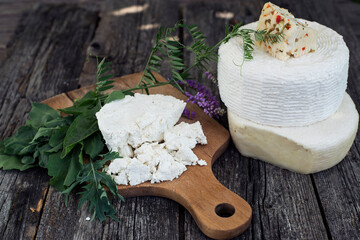 Ricotta cheese on a cutting board, cheese heads, arugula and spinach.