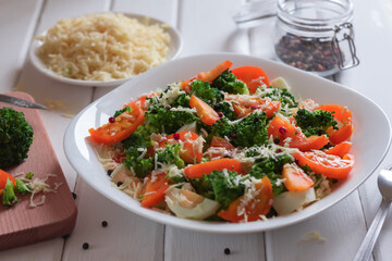 salad of tomatoes, broccoli and cheese in a white plate on the table