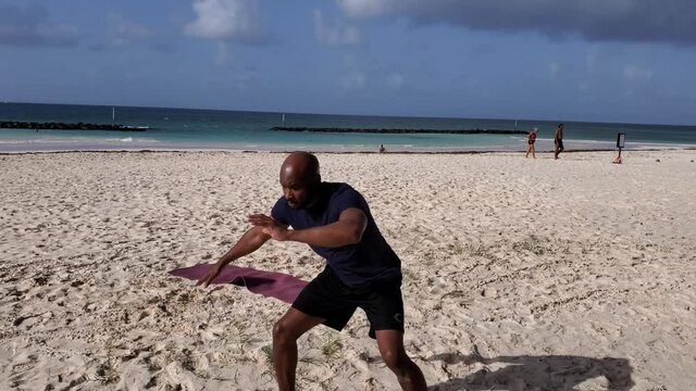 Black man African American doing Brazil capoeira martial arts on beach
