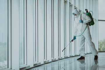 Coronavirus Pandemic. A disinfector in a protective suit and mask sprays disinfectants inoffice....