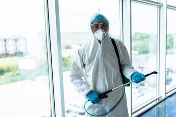 Man disinfector worker cleaning office space and window before work on corona virus pandamia.