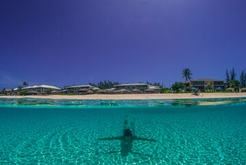 A young lady enjoys swimming in the perfectly blue Caribbean sea on Seven Mile Beach in Grand Cayman