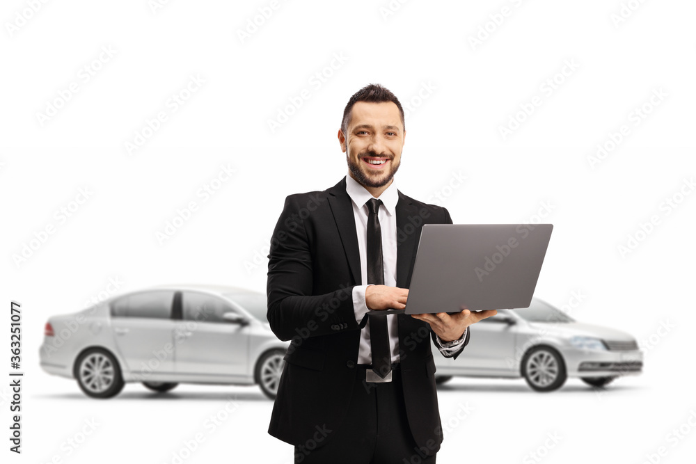 Sticker man in a suit with a laptop computer smiling at the camera and posing in front of cars