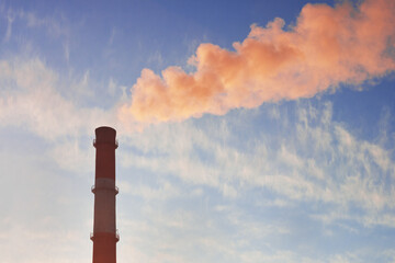 Chimney with red smoke against the background of a sunset sky. Ecology, environmental pollution,...