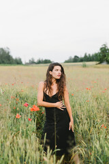 Beautiful woman in a black linen dress in a poppy field. Fashion concept.