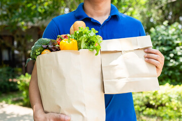 Asian deliver man holding bag of food, fruit, vegetable give to costumer in front of the house. Postman giving.stay at home concept.