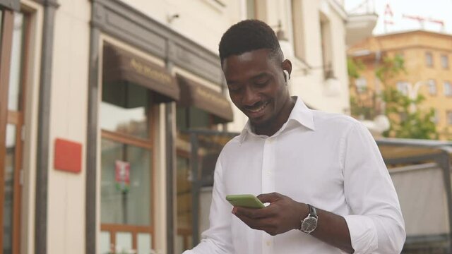 Portrait of a young african american businessman in white shirt using smartphone in the city