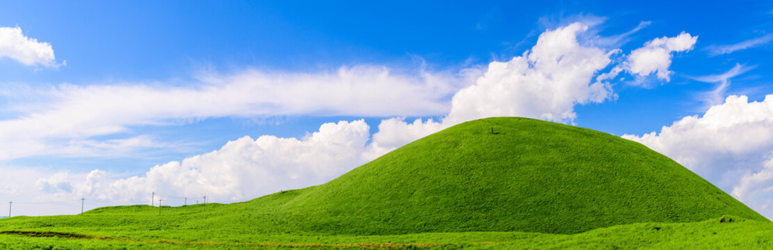 米塚火山風景　パノラマ写真
阿蘇山への道に米塚火山の名残
初夏・新緑の晴天の美しい風景
高さ80メートルの小さな山ですが、れっきとした火山です
頂上の窪みは噴火の名残です。
Yonezuka volcano landscape panoramic photo
The remains of Yonezuka volcano on the way to Mt. Aso