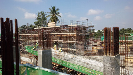 SEREMBAN, MALAYSIA -MARCH 29, 2020: Construction workers fabricating steel reinforcement bar at the construction site. They tied it together using the tiny wires. It is one of the steps in making of r