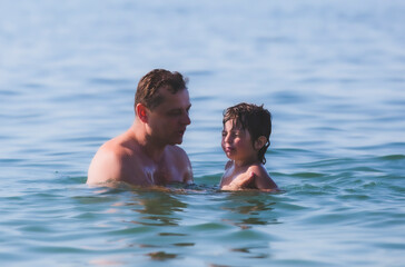 dad with his son are swimming in the sea.Sunny day. Mediterranean Sea.
