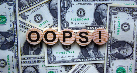 Oops sign on wooden cut circles. Beautiful background from dollar bills. Concept.