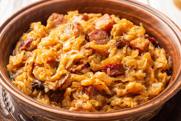 Traditional Polish dish Bigos in ceramic bowl on rustic wooden table