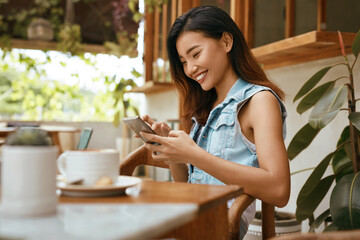 Business. Woman At Coffee Shop Using Smartphone. Beautiful Asian Model In Stylish Outfit Enjoying Summer Vacation At Cafe. Comfortable Communication With Modern Digital Technologies.