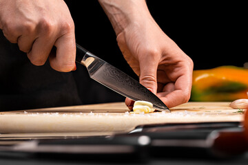 Closeup of hands of chef cook cutting vegetables on wooden table