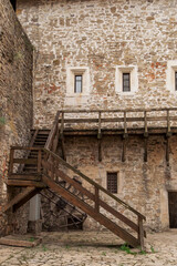 Fototapeta na wymiar A wooden staircase in the courtyard of a stone medieval castle.