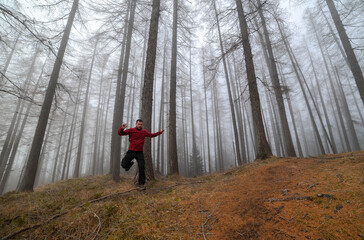 Red jacket hiker running in a misty forest