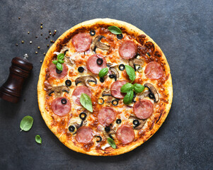 Pizza with salami, mushrooms and tomato sauce on a black background. View from above.