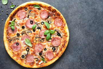 Pizza with salami, mushrooms and tomato sauce on a black background. View from above.