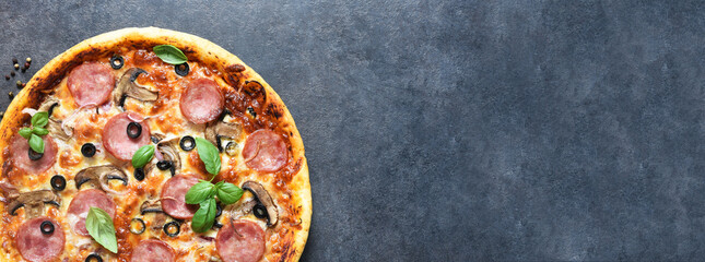 Pizza with salami, mushrooms and tomato sauce on a black background. View from above.