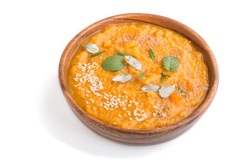 Sweet potato or batata cream soup with sesame seeds in a wooden bowl isolated on a white background. side view.