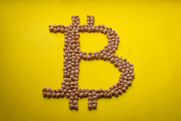 Bitcoin Sign Made with Chickpeas on a Yellow Background Table