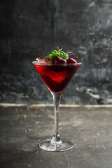 Cherry cocktail in martini glass with berries and mint leaves. Selective focus. Shallow depth of field.
