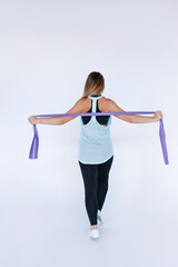 Fototapeta premium Beautiful athletic girl doing an exercise with tape . 