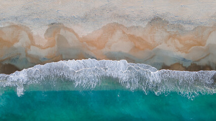 Aerial View Above Sandy Beach Seashore of Clear Blue Aqua Waves Breaking on Shore at Dusk Sunset Creating Beautiful Ocean coast tropical background texture with white sea foam