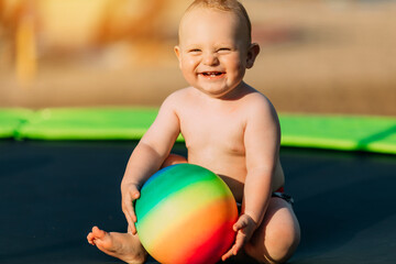 Little laughing kid playing with balls on the beach in the play area, summer vacation