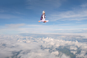 A beautiful girl is flying in the sky above white clouds.
