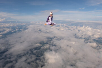 Fototapeta na wymiar A beautiful girl is flying in the sky above white clouds.