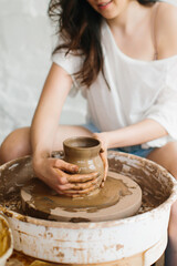 Woman sculpts jug of clay. Work on pottery wheel. Ceramics production.