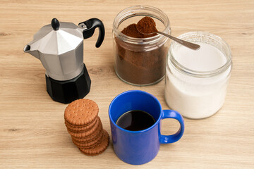 Good morning with coffee. A cup of coffee in blue. Biscuits. Coffee maker.. Sunny.