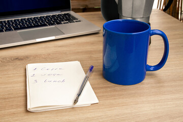 Good morning with coffee. A cup of coffee in blue. Notepad with daily routine. Notebook.. Sunny.