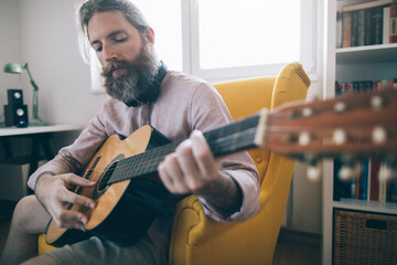 Bearded man playing guitar. Hipster man enjoy acoustic guitar at his home