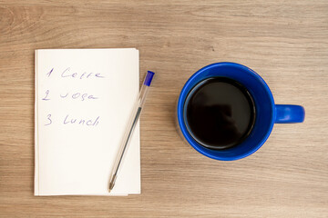 Good morning with coffee. A cup of coffee in blue. Notepad with daily routine. . Sunny.
