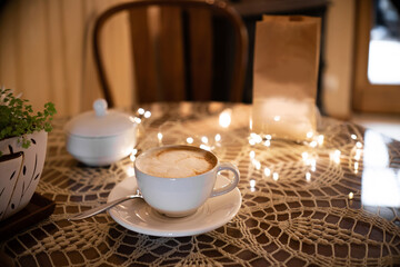 Coffee pouch mockup with coffee cup and milk on dark romantic background. Paper clear bag in candles light