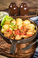 Fried pieces of chicken with red peppers and onions.